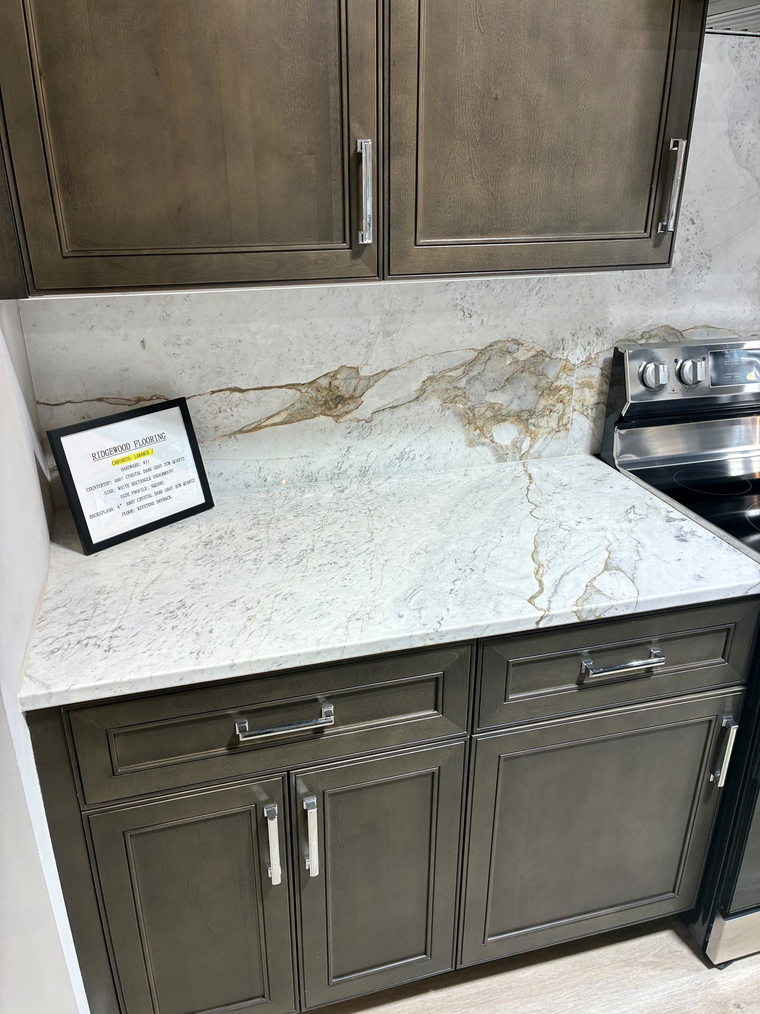 Grey-brown cabinetry with range and stone backsplash